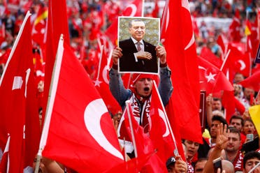 A supporter of Turkish President Tayyip Erdogan holds up a picture during a pro-government protest in Cologne, Germany July 31, 2016. REUTERS