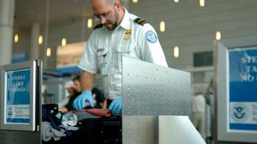 A TSA agent searches luggage at an airport. (Shutterstock)