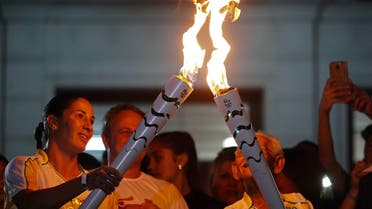 One athlete relays the Olympic torch to another in the streets of Sao Jose dos Campos. (Reuters)