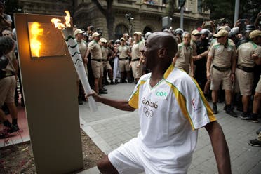 Street sweeper Renato Sorriso smiles while lighting the first of five posts with the Olympic torch in Rio de Janeiro. (Reuters)