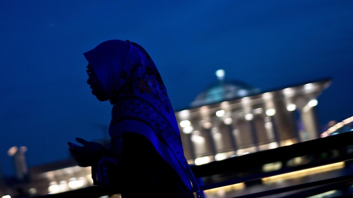 A Malaysian girls walks along the waterfront during sunset against the backdrop of the Iron Mosque in Putrajaya on May 10, 2015. AFP
