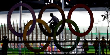 A man climbs on the Olympic rings near the basketball venue in the Olympic park on th eve before the opening ceremony of the 2016 Summer Olympics in Rio de Janeiro, Brazil, Thursday, Aug. 4, 2016. (AP)