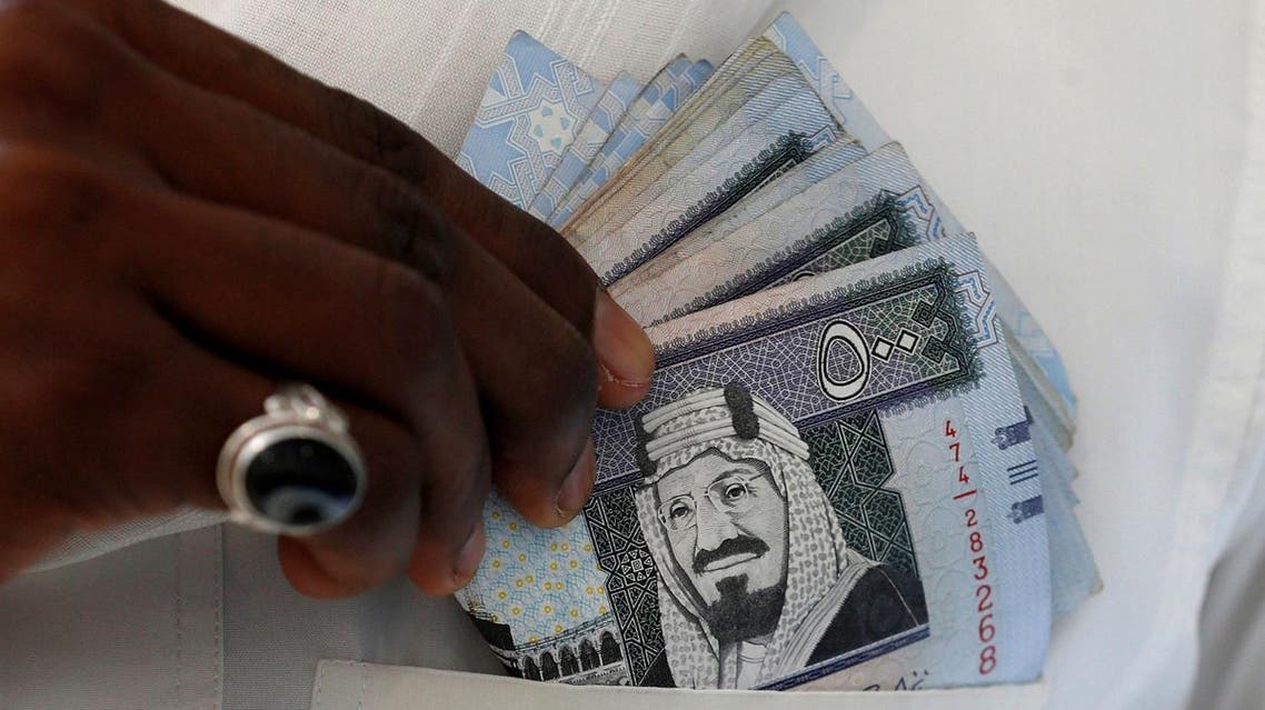 A Saudi man shows Saudi riyal banknotes at a money exchange shop, in Riyadh. (Reuters)
