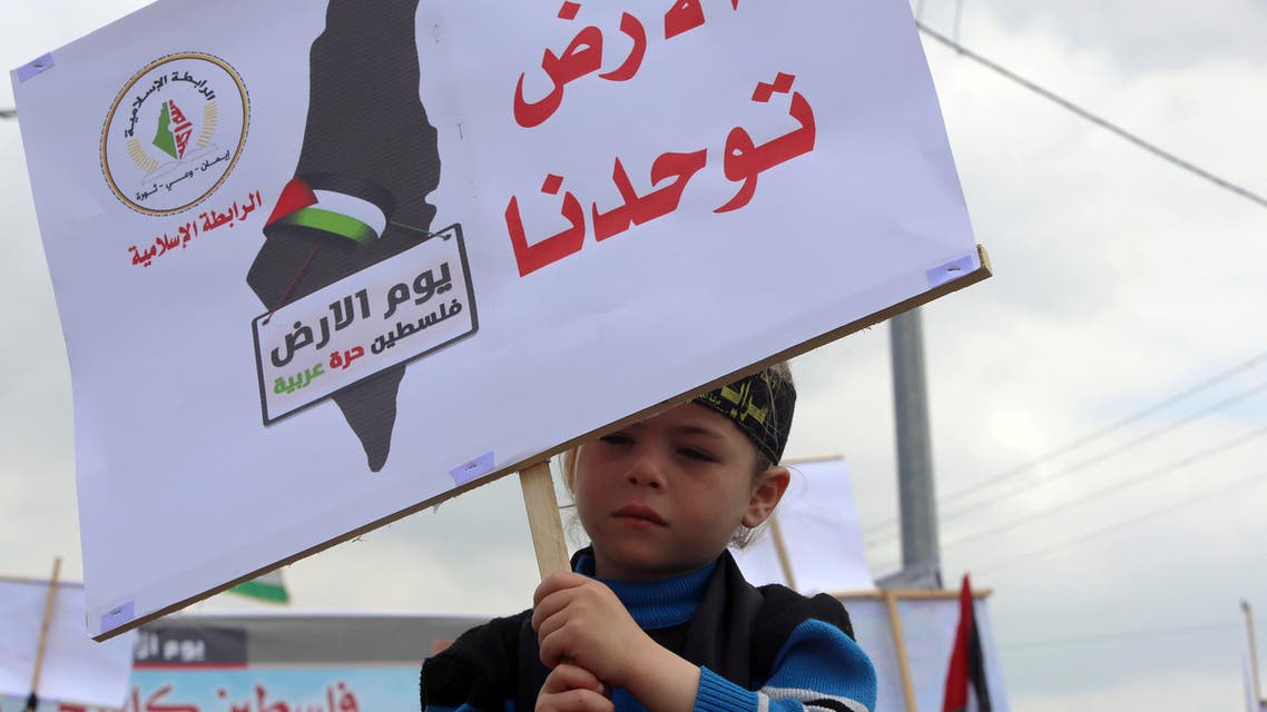 A Palestinian boy holds a banner that reads Land Unites Us, on Land Day, Palestine is Arab, Free during a rally organized by Palestinian factions marking the 40th anniversary of Land Day. (File AP)