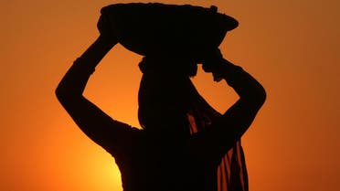 In a 2012 file photo, a woman labourer carrying cement is silhouetted against the setting sun at the site of a commercial complex on the outskirts of Jammu. (Reuters)