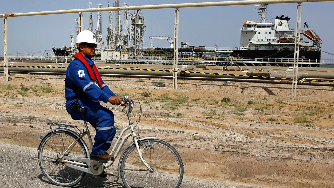 An Iraqi engineer rides a bicycle past a gas carrier as it prepares to set sail at the southern port of Umm Qasr, near Basra, Iraq, Sunday, March 20, 2016.