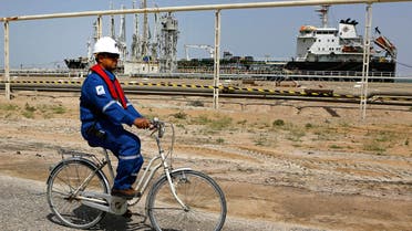 An Iraqi engineer rides a bicycle past a gas carrier as it prepares to set sail at the southern port of Umm Qasr, near Basra, Iraq, Sunday, March 20, 2016. 