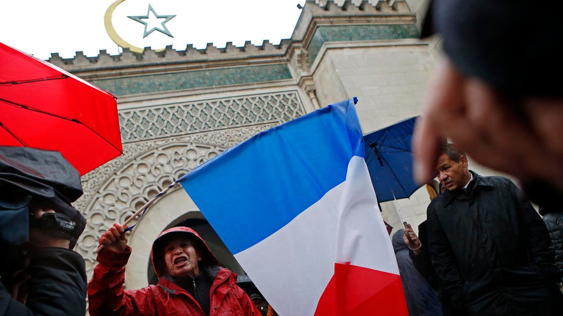 A French Muslim, of Algeria origin, who wants to be named "Cherif" talks to the media, holding a French flag, in front of the Great Mosque of Paris after the Friday priest, in Paris, France, Friday, Nov. 20, 2015 one week after the Paris attacks.ap