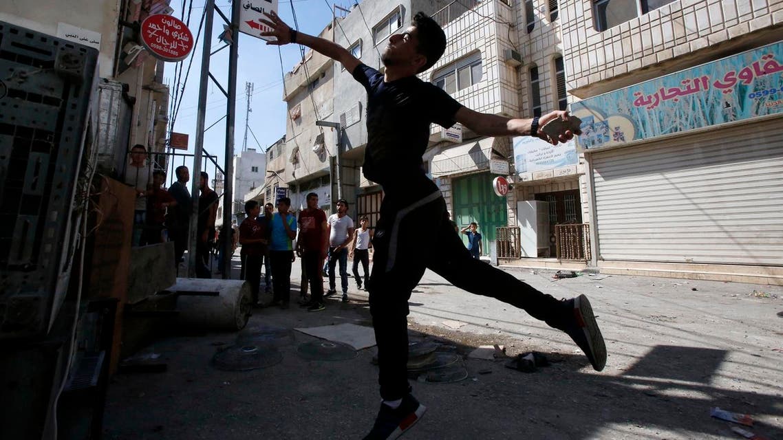 A Palestinian youth throws stones towards Israeli soldiers as they conduct searches in the Palestinian al-Fawwar refugee camp, south of the West Bank city of Hebron, on August 16, 2016. Twenty-five Palestinians were wounded in clashes with Israeli soldiers conducting searches in a refugee camp in the southern West Bank on Tuesday, Red Crescent medics said. Some of the wounded had been hit by live ammunition, others by rubber bullets, the medics said. An Israeli army spokeswoman said the troops were conducting "activity to uncover weaponry" in the camp, when "dozens of Palestinians hurled IEDs (improvised explosive devices), blocks and rocks" at them. HAZEM BADER / AFP