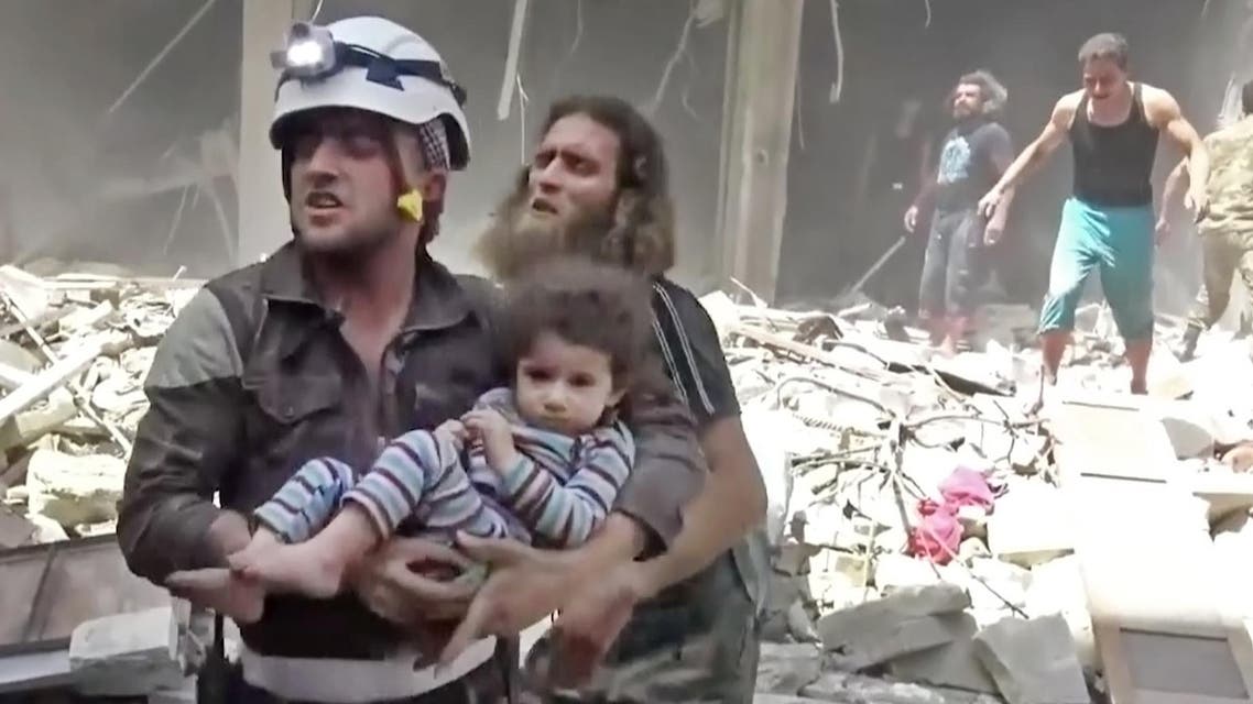 In this image made from video and posted online from Validated UGC, a Civil Defense worker carries a child after airstrikes hit Aleppo, Syria, Thursday, April 28, 2016. AP