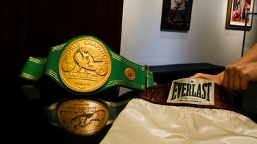 A woman arranges the short and the iconic 'Rumble in the Jungle' belt of late boxing champion Muhammad Ali at Heritage Auctions house in Manhattan, New York, US. (Reuters)