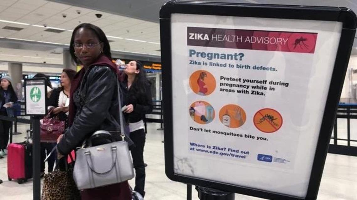 A woman looks at a Center for Disease Control (CDC) health advisory sign about the dangers of the Zika virus as she lines up for a security screening at Miami International Airport in Miami, Florida, U.S., May 23, 2016. REUTERS