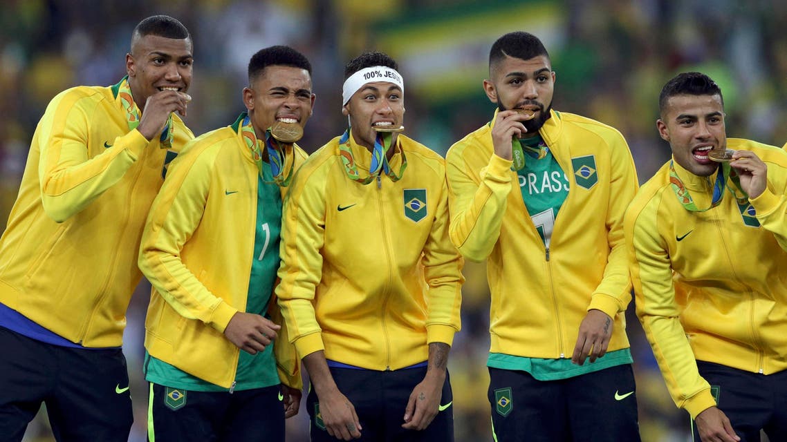 Neymar (BRA) of Brazil and teammates bite their gold medals. REUTERS