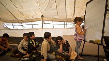  Syrian refugee Ghufran Ahmad, 5, writes on a board while she and other children attend a class at a makeshift school set up in a tent at an informal tented settlement in the Jordan Valley, Jordan, Thursday, March 31, 2016. (AP Photo/Muhammed Muheisen)