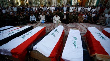Iraqi civilians and soldiers mourn next to coffins containing the remains of ten of their comrades who were killed in the Speicher massacre, after they were handed over to relatives following weeks of examination to check their identities via DNA tests, during their funeral procession in the holy Iraqi city of Najaf on July 1, 2015. AFP