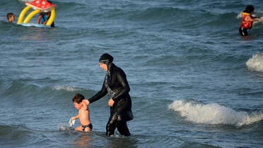A Tunisian woman wearing a “burkini”, a full-body swimsuit designed for Muslim women, walks in the water with a child on Aug. 16, 2016 (File Photo: AFP)