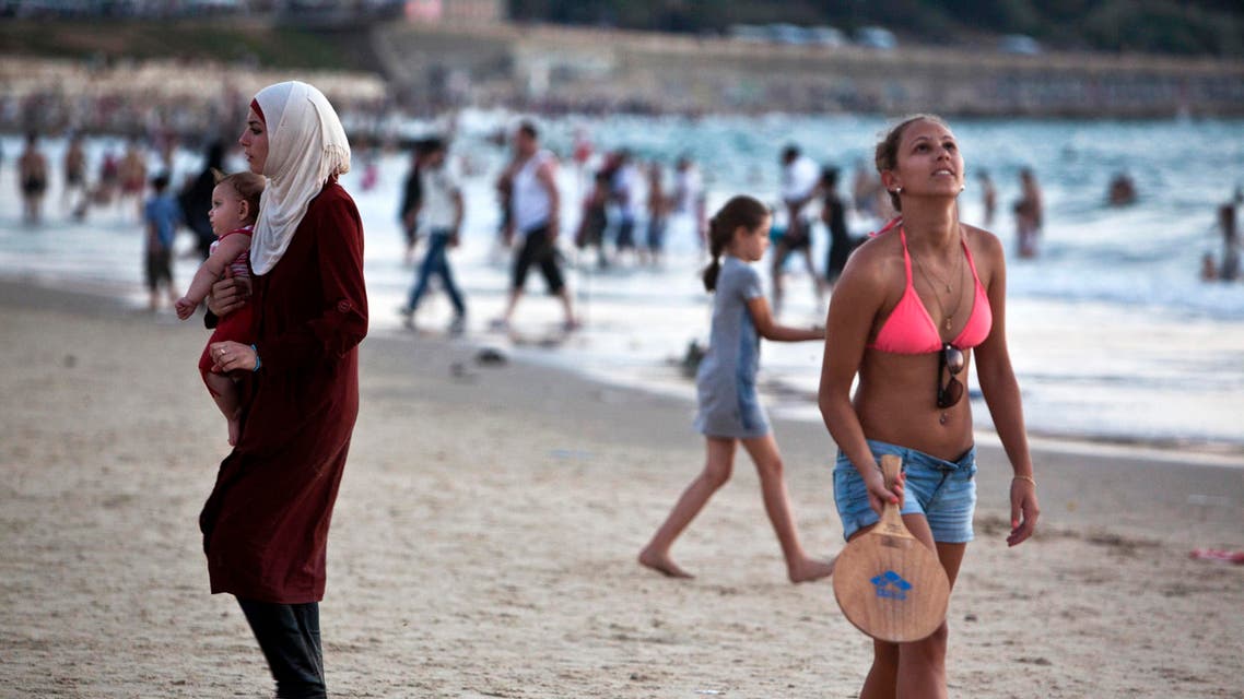 A Palestinian woman (L) holds a baby as she visits a beach in Tel Aviv during Eid al-Fitr, which marks the end of the holy month of Ramadan August 20, 2012. Reuters