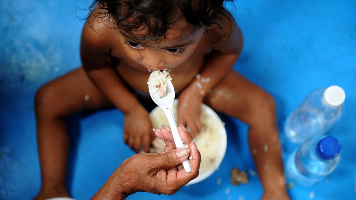 A mother feeds her daughter with food provided by the Philippine National Red Cross (PNRC) at the Delpan Sports complex in Manila on May 18, 2012. AFP