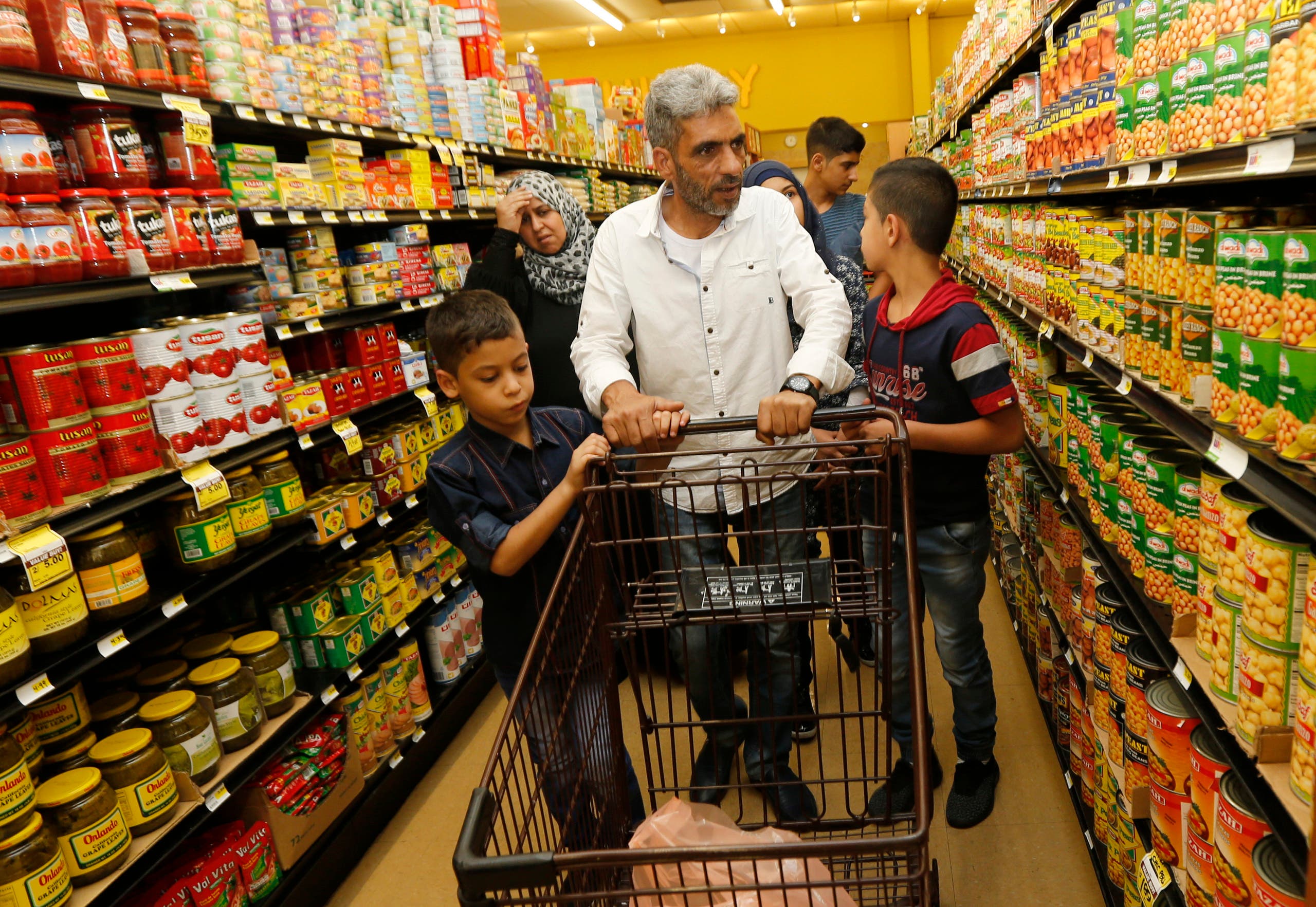 Nadim Fawzi Jouriyeh, a Syrian refugee who arrived in the United States this week with his family, pushes a shopping cart with sons, Farouq Nadim Jouriyeh, left, and Hamzeh Nadim Jouriyeh, Wednesday, Aug. 31, 2016, in El Cajon, Calif. Days after participating in a ceremony in Jordan to mark the United States hitting its target of taking in 10,000 Syrian refugees, the former construction worker and his family buy roasted chicken, milk and fruit for their new home outside San Diego. (AP Photo/Lenny Ignelzi)