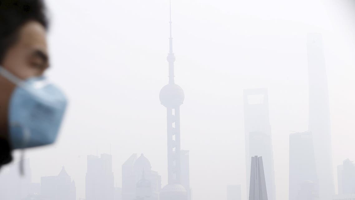 A man wearing a face mask walks on a bridge in front of the financial district of Pudong amid heavy smog in Shanghai, China, in this December 15, 2015 file photo. reuters