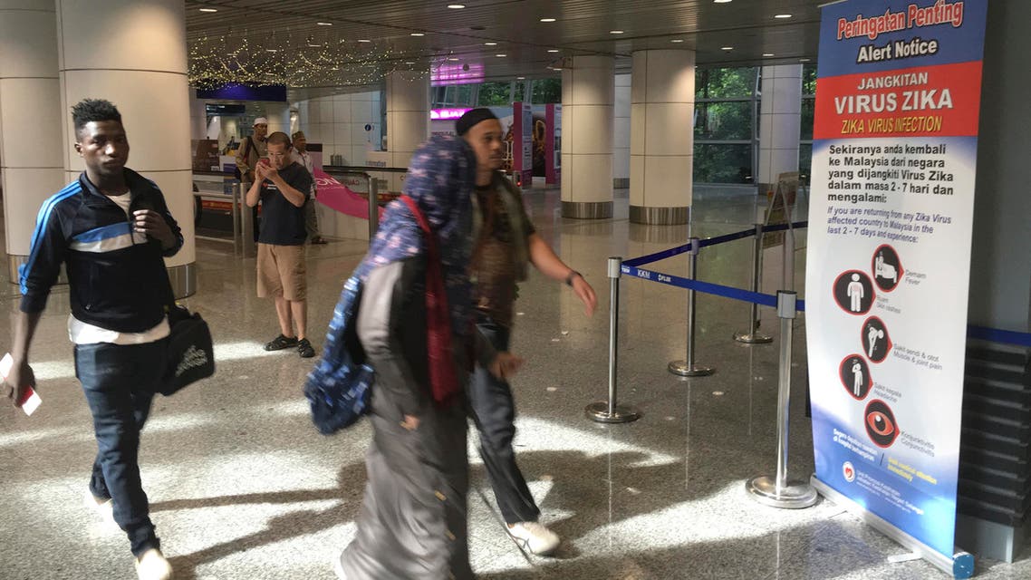 Travelers walk past a travel advisory on the Zika virus infection in Kuala Lumpur International Airport in Sepang, Malaysia, Sunday, Aug. 28, 2016. (AP)
