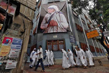 Nuns belonging to the global Missionaries of Charity, walk past a large banner of Mother Teresa ahead of her canonisation ceremony, in Kolkata, India September 3, 2016. REUTERS