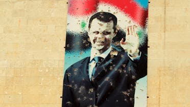 A damaged picture of Syrian president Bashar Al-Assad is seen on a wall in Idlib city, after rebel fighters took control of the area March 28, 2015. The text on the poster reads in Arabic "With Bashar". Picture taken March 28, 2015. REUTERS/Ammar Abdallah