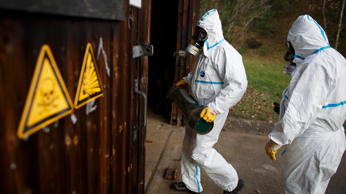 Employees in protective clothing carry a dummy grenade during a demonstration in a chemical weapons destruction facility at GEKA (Gesellschaft zur Entsorgung von chemischen Kampfstoffen und Ruestungsaltlasten) in Munster, northern Germany, on October 30, 2013. AFP