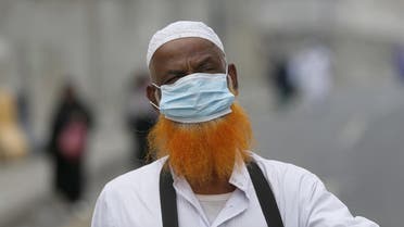 A Muslim pilgrim covers his face with a mask as he walks in the streets of Saudi Arabia's holy city of Makkah. (AFP)