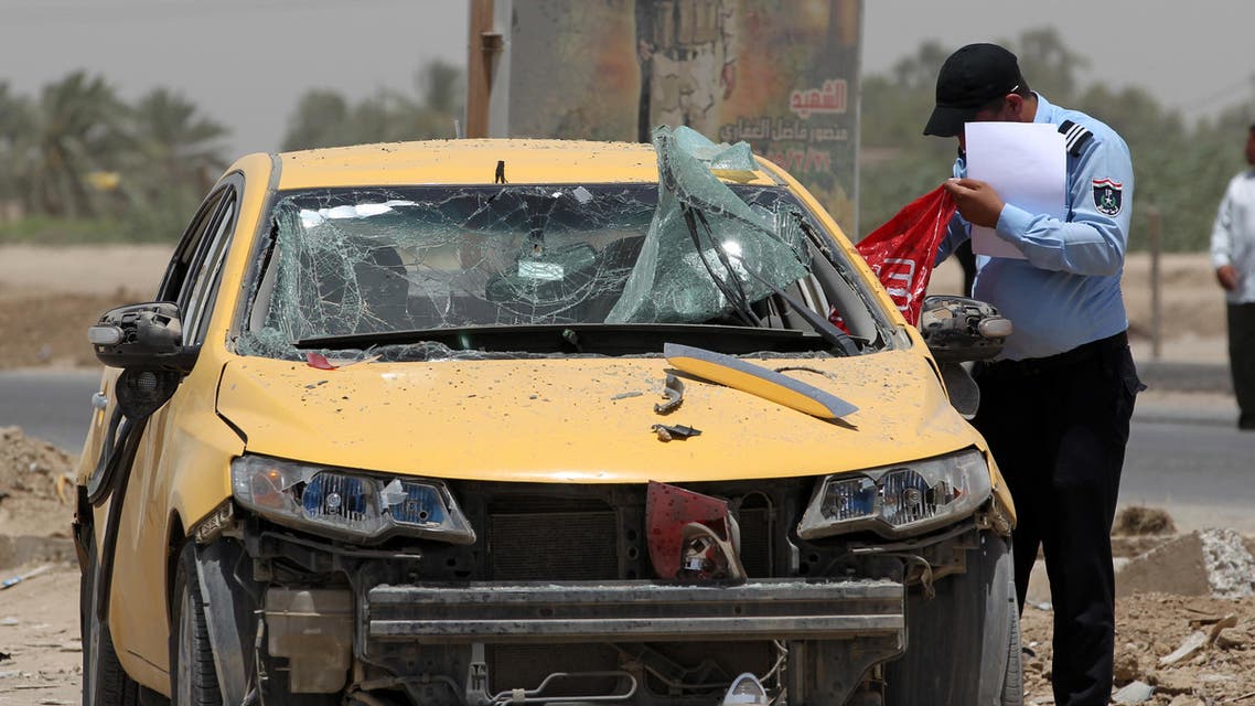 An Iraqi policeman looks at a damaged car as he inspects the site of a suicide bomb attack, claimed by the Islamic State group, at a checkpoint leading to the Husseiniyah area, northeast of the capital Baghdad on July 13, 2016. A suicide bomber detonated an explosives-rigged vehicle killing at least four people and wounding 21 people, the officials said. AFP