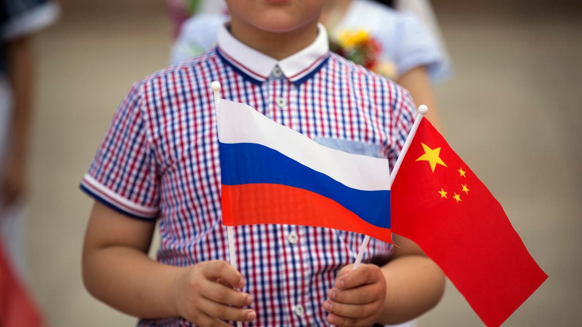 A boy holds Russian, left, and Chinese flags before a welcoming ceremony for Russian President Vladimir Putin at the Great Hall of the People in Beijing. (File Photo: AP)