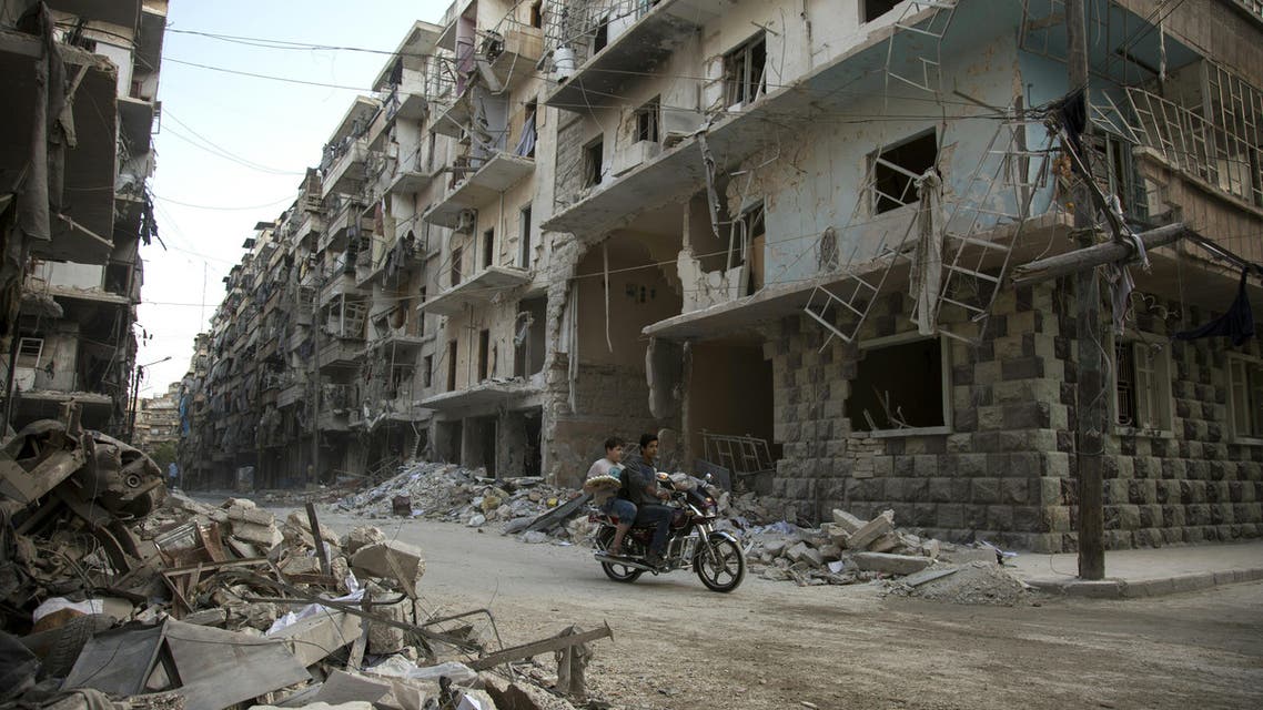 Syrian men ride a motorbike past damaged buildings in the rebel-held Bustan al-Qasr district in eastern Aleppo, on May 4, 2016.