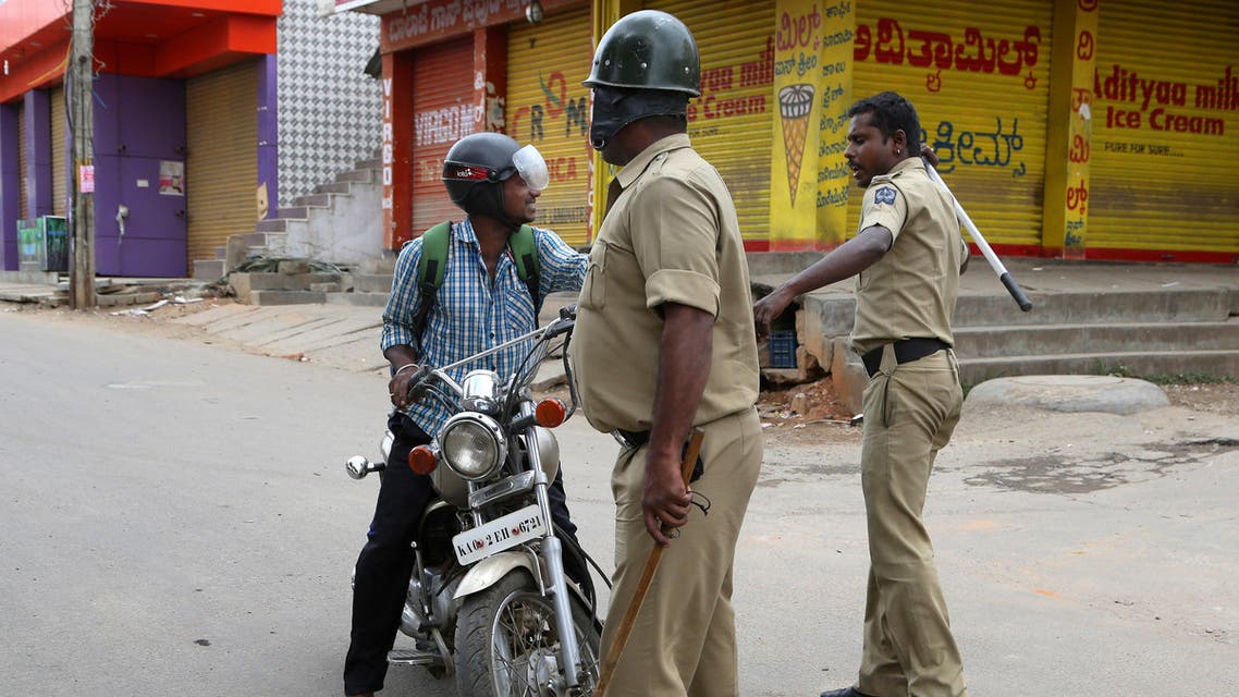 An Indian policeman hits a motorcyclist for defying curfew, a day after angry mobs burnt and vandalized buses from the neighboring Tamil Nadu state, in Bangalore, capital of the southern Indian state of Karnataka, Tuesday, Sept. 13, 2016. AP