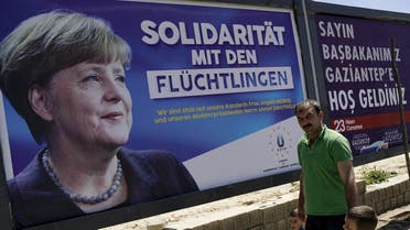 People walk past a banner with picture of German Chancellor Angela Merkel on a main street in Gaziantep, Turkey, April 23, 2016. The banner in German reads, "Solidarity with refugees. We are proud of our Chancellor Angela Merkel and Prime Minister Ahmet Davutoglu". REUTERS