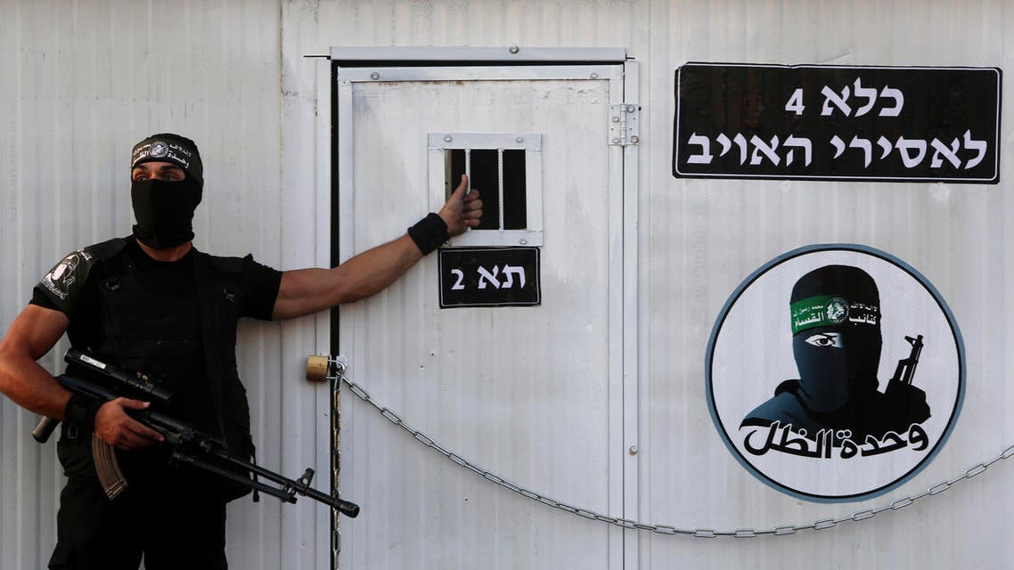 A Palestinian masked member from the Izzedine al-Qassam Brigades, a military wing of Hamas, stands guard in front of a mock jail for Israeli soldiers during a rally in Rafah refugee camp, Gaza Strip, Sunday, Aug. 21, 2016. (AP)