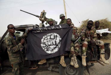 جنود نيجيريون يحملون راية رفعها بوكو حرام على أحد مقاره (رويترز)
