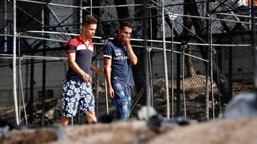 A migrant (R) reacts as he walks next to the remains of burned tents at the Moria migrant camp, after a fire that ripped through tents and destroyed containers during violence among residents. (Reuters)