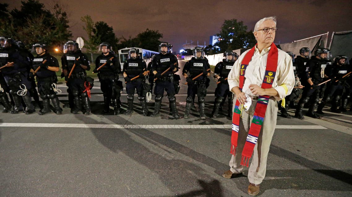 A member of the clergy stands in front of a line of police officers in Charlotte, N.C. Thursday, Sept. 22, 2016. blocking the access road to I-277 on the third night of protests following Tuesday’s fatal police shooting of Keith Lamont Scott. (AP)