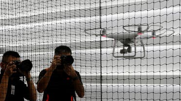 Photographers take photos of a drone flying at DJI's flagship store in Hong Kong, China September 22, 2016, two days before its opening. REUTERS