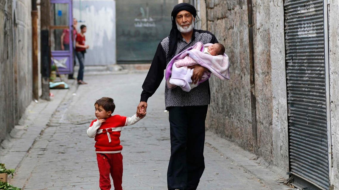 Abu Ahmad carries his baby, Jalal, while walking with his daughter Amal in the Al-Shaar neighbourhood of Aleppo. (File photo: Reuters)