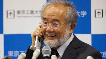 Nobel Prize winner Yoshinori Ohsumi smiles as he speaks with Japanese Prime Minister Shinzo Abe on a mobile phone during a press conference at the Tokyo Institute of Technology in Tokyo Monday, Oct. 3, 2016. AP