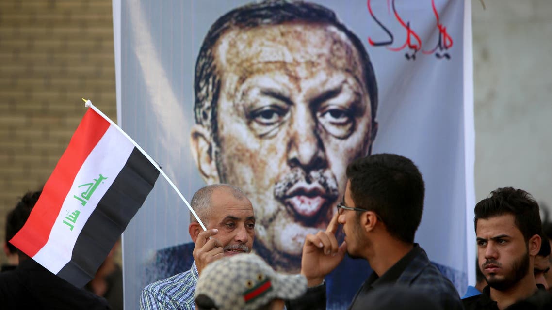 Iraqis, one with a national flag, stand in front of a banner bearing a portrait of Turkish President Recep Tayyip Erdogan during a demonstration to demand the withdrawal of the Turkish troops from the Bashiqa camp, located in the Mosul province, on October 8, 2016 outside the Turkish Embassy in Baghdad. Turkey said on October 6, 2016 that its troops will remain in Iraq despite Baghdad's growing anger ahead of a planned operation to retake the Iraqi city of Mosul from Islamic State group jihadists. Turkey has an estimated 2,000 troops in Iraq -- around 500 of them in the Bashiqa camp in northern Iraq training Iraqi fighters who hope to participate in the battle to recapture Mosul, according to Turkish media. (AFP)