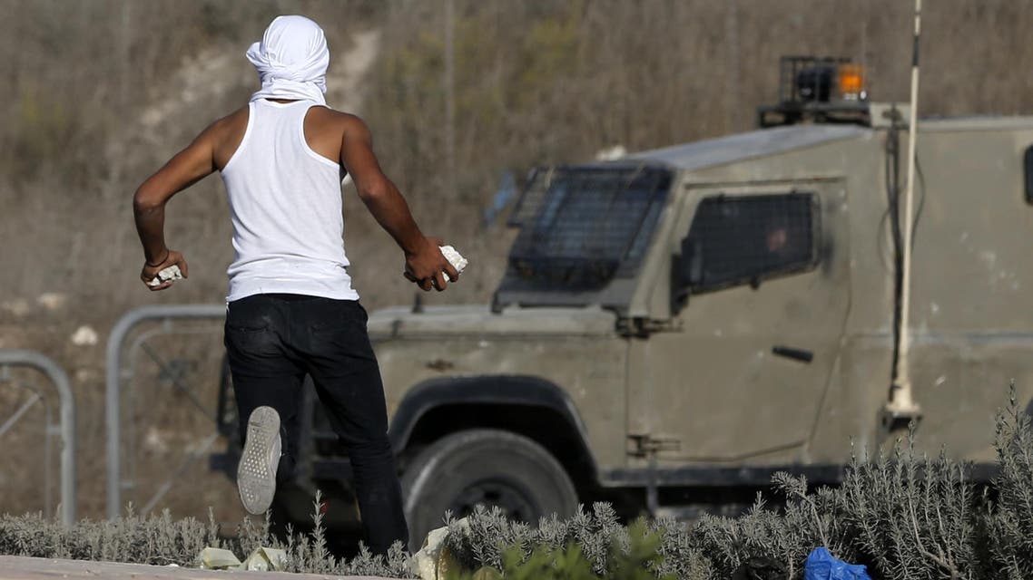 A masked Palestinian youth prepares to throw stones towards Israeli security forces during clashes in the West Bank town of al-Ram, north of Jerusalem, on October 9, 2016. (AFP)