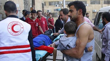 A Syrian man carries a child as they await treatment at a hospital in the regime-held part of Aleppo. (AFP)