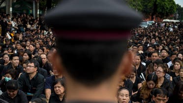 A large crowd clad in black who came to pray for the late Thai King Bhumibol Adulyadej is watched by a Thai policeman in front of the Grand Palace in Bangkok on October 16, 2016 AFP