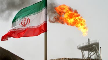 A gas flare on an oil production platform in the Soroush oil fields is seen alongside an Iranian flag in the Persian Gulf, Iran, July 25, 2005. REUTERS/Raheb Homavandi/File Photo