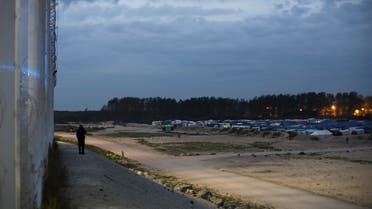 A migrant uses a phone near the fence built along a highway, in a makeshift camp near Calais, France, Thursday, Oct. 13, 2016. (AP)