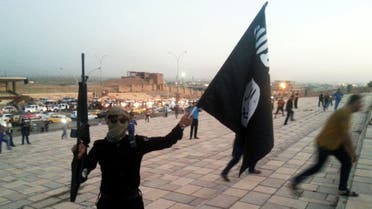 A fighter of the Islamic State of Iraq and the Levant (ISIL) holds an ISIL flag and a weapon on a street in the city of Mosul June 23, 2014. (AP)