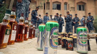 Iraqi policemen lay out cans of beer, alcohol, and weapons seized in a raid in the district of Tanouma on the outskirts of the southern Iraqi city of Basra, near the Iranian border on June 6, 2009. AFP