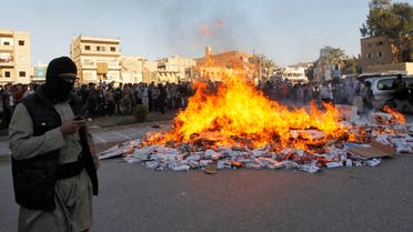 An ISIS fighter stands near burning confiscated cigarettes in the city of Raqqa April 2, 2014. (Reuters)